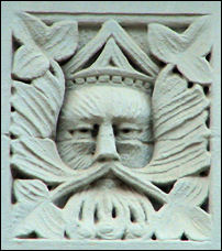 On the first storey faade between shop frontages there are two panels depicting Green-Man type faces,