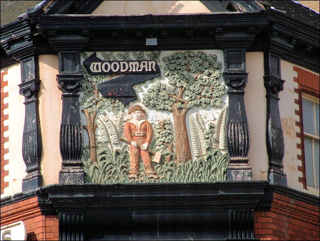 A large relief depicting a man in brown clothing holding in an axe, against a background of trees and foliage. 
